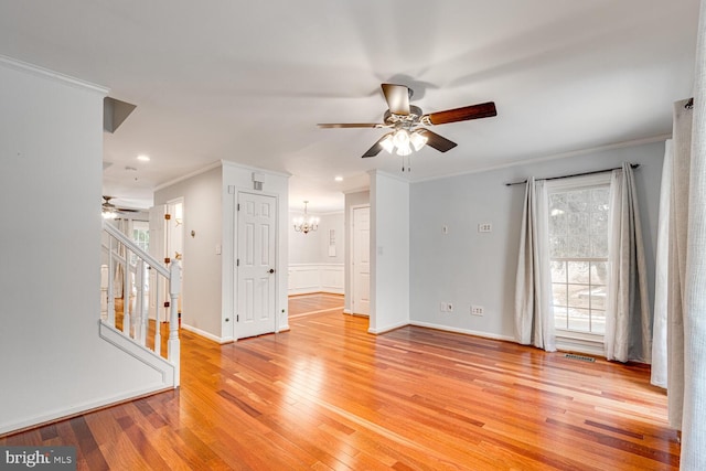 empty room with light hardwood / wood-style floors, ceiling fan with notable chandelier, and ornamental molding