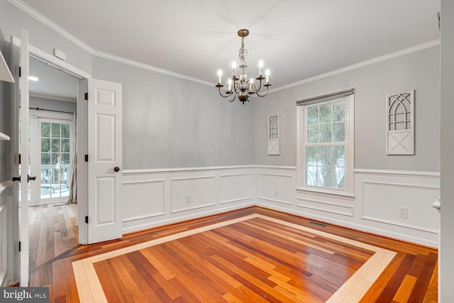 unfurnished room featuring hardwood / wood-style flooring, an inviting chandelier, and ornamental molding