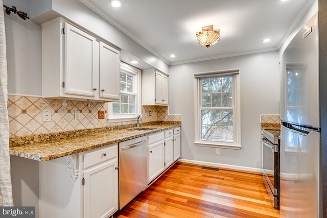 kitchen featuring white cabinets, stainless steel appliances, light hardwood / wood-style flooring, and light stone countertops