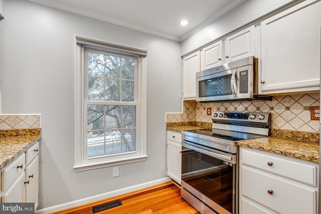 kitchen with light stone counters, white cabinets, stainless steel appliances, and tasteful backsplash