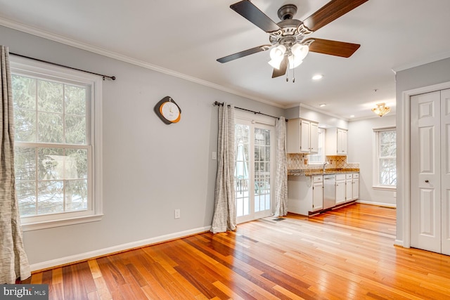 kitchen featuring stainless steel dishwasher, tasteful backsplash, light wood-type flooring, and white cabinets