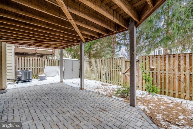 snow covered patio with a storage unit and central AC unit