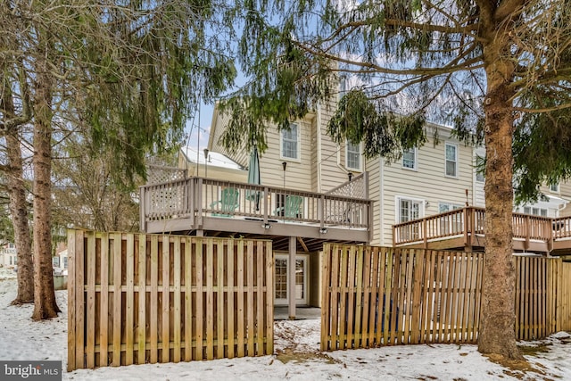 snow covered back of property with a wooden deck