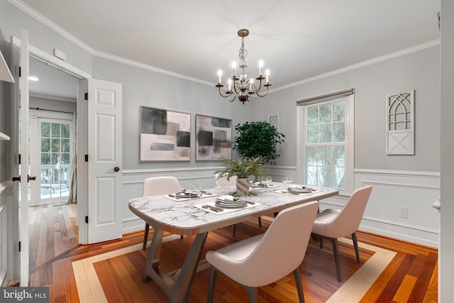 dining area with a notable chandelier, hardwood / wood-style flooring, ornamental molding, and plenty of natural light