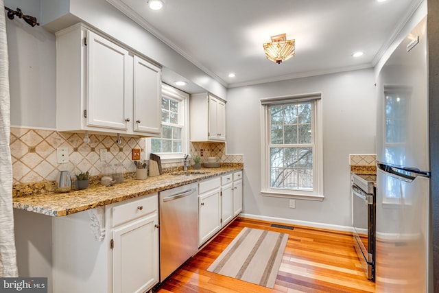 kitchen featuring white cabinets, light hardwood / wood-style flooring, and appliances with stainless steel finishes