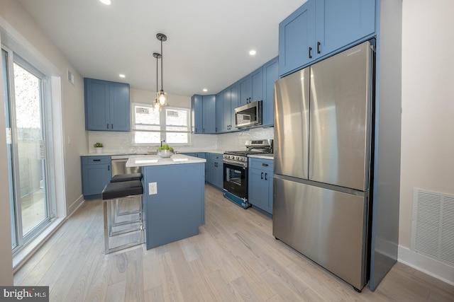 kitchen featuring a center island, a breakfast bar, light hardwood / wood-style flooring, hanging light fixtures, and appliances with stainless steel finishes