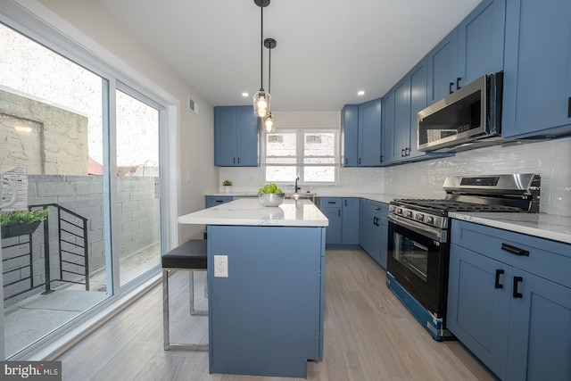 kitchen with appliances with stainless steel finishes, blue cabinetry, and a kitchen island