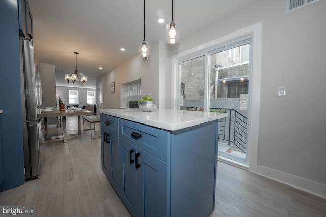 kitchen featuring a kitchen island, an inviting chandelier, hanging light fixtures, light wood-type flooring, and stainless steel fridge