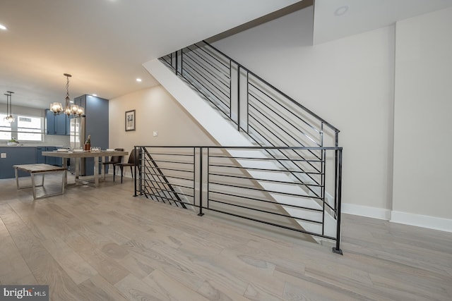 stairs with wood-type flooring and a chandelier