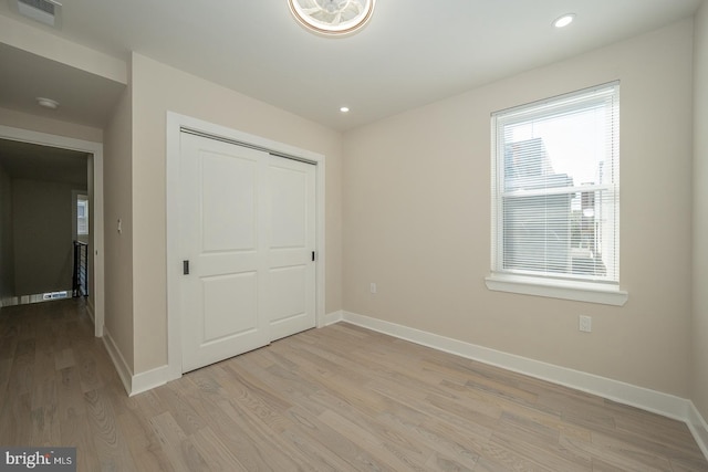 unfurnished bedroom with a closet and light wood-type flooring