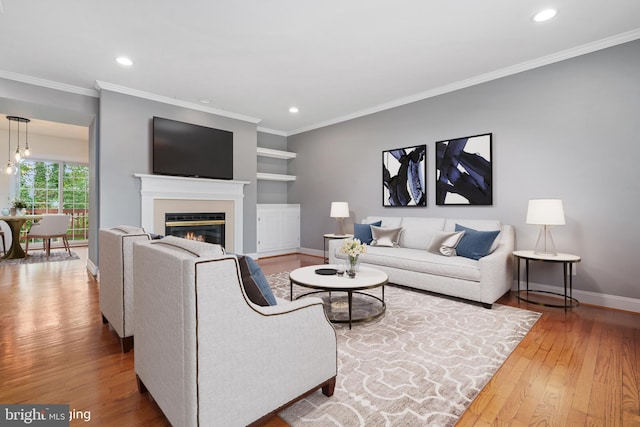 living room with hardwood / wood-style flooring, built in shelves, and crown molding