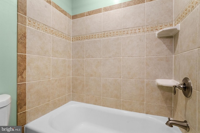 bathroom with toilet and tiled shower / bath