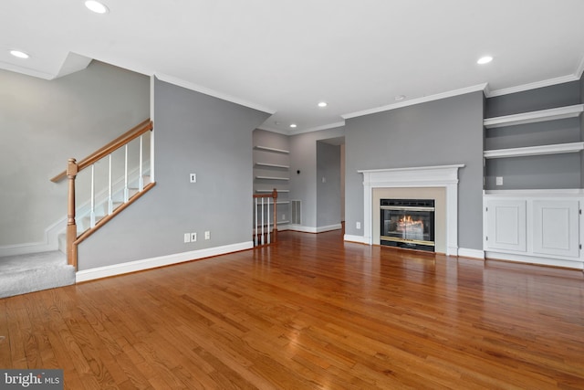 unfurnished living room featuring wood-type flooring, built in features, and ornamental molding