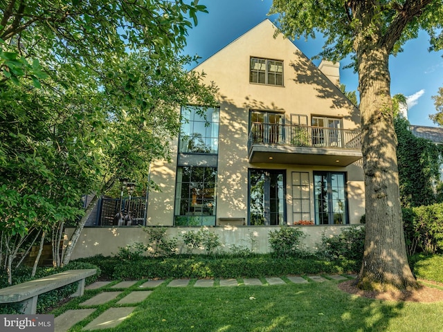 view of front facade with a balcony and a front lawn