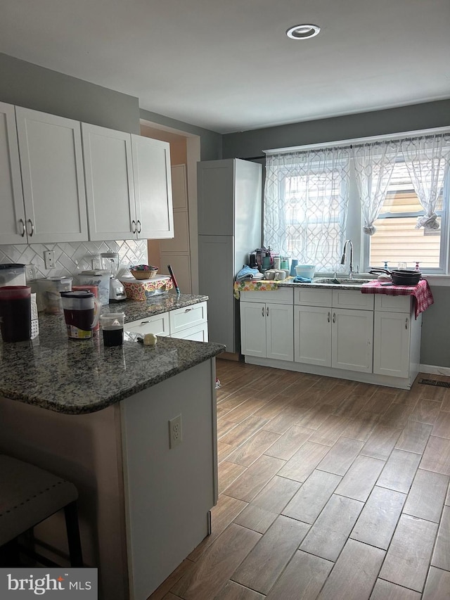 kitchen with sink, white cabinetry, plenty of natural light, and dark stone countertops