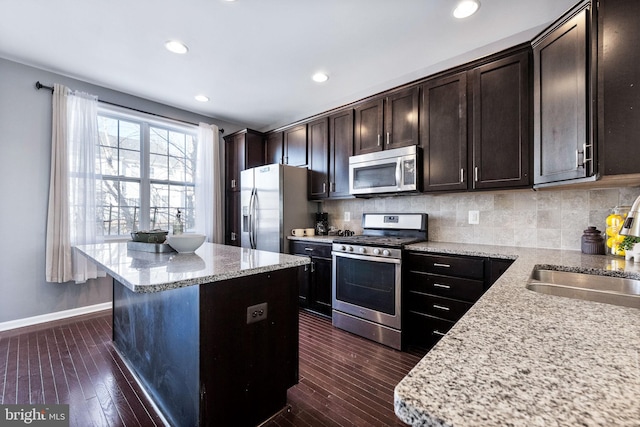 kitchen featuring light stone countertops, sink, stainless steel appliances, and dark brown cabinets