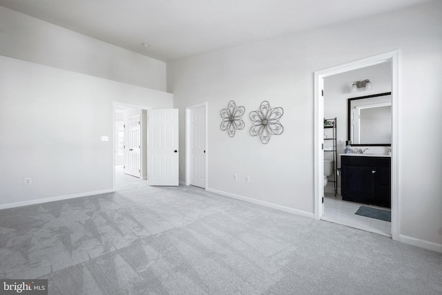 unfurnished bedroom featuring sink, ensuite bathroom, and light carpet