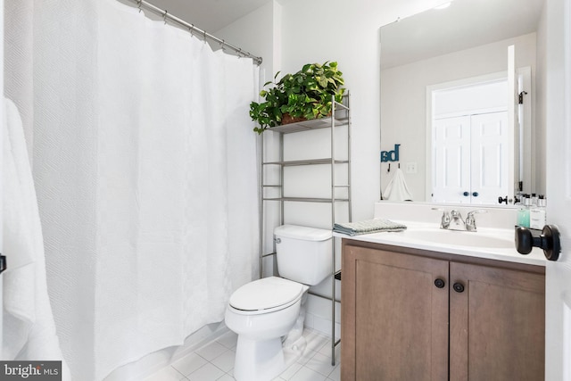 bathroom with toilet, vanity, and tile patterned flooring