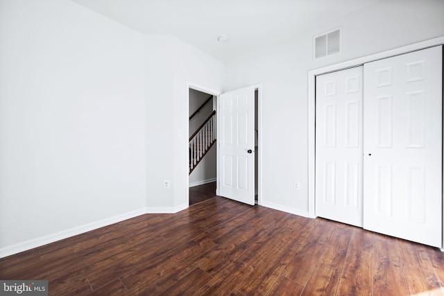 unfurnished bedroom with a closet and dark wood-type flooring