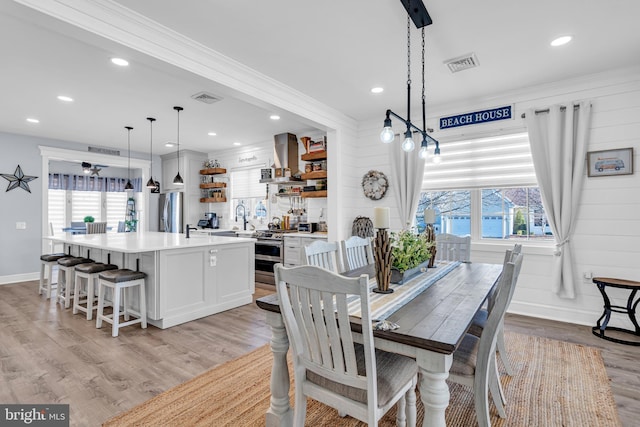 dining area with light wood-type flooring, a wealth of natural light, crown molding, and sink