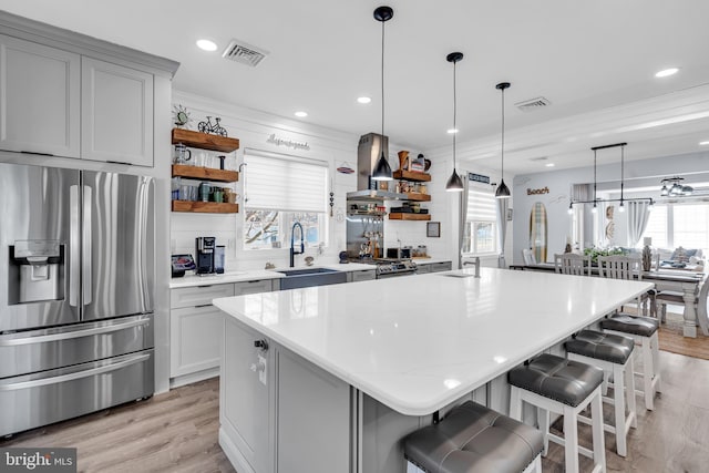 kitchen with island range hood, appliances with stainless steel finishes, a center island, a breakfast bar, and sink