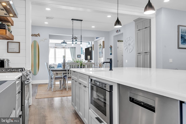 kitchen featuring light stone countertops, pendant lighting, gray cabinets, and gas stove