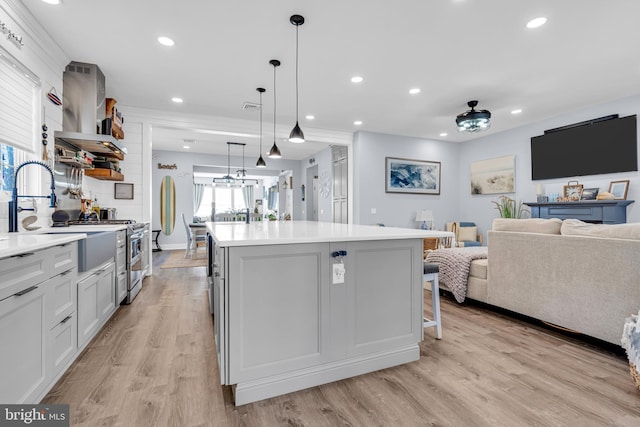 kitchen featuring white cabinetry, hanging light fixtures, light wood-type flooring, and a kitchen island