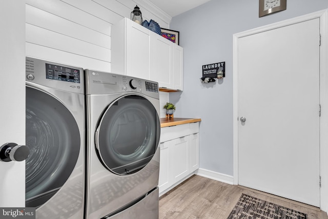 washroom featuring cabinets, washing machine and dryer, and light wood-type flooring