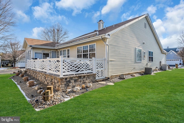 back of house with central AC unit and a yard