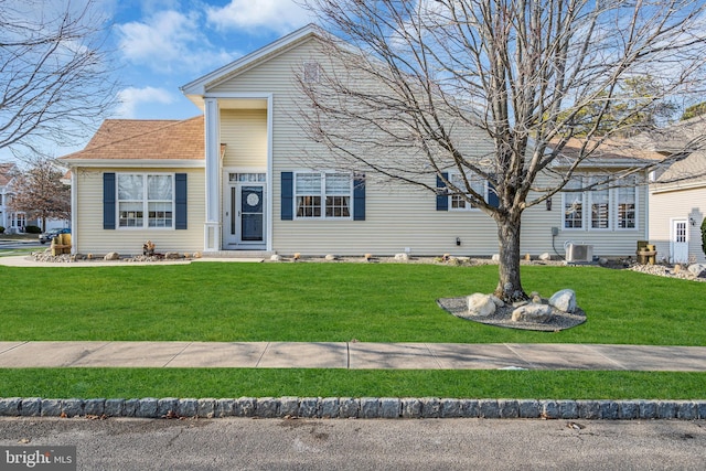 view of front of property with a front lawn and central AC