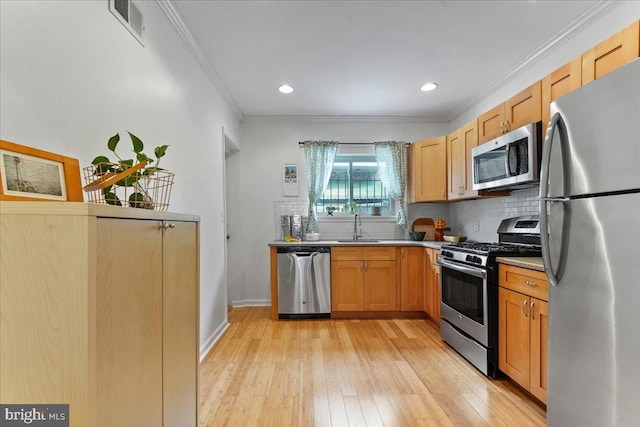 kitchen featuring tasteful backsplash, sink, crown molding, light wood-type flooring, and appliances with stainless steel finishes