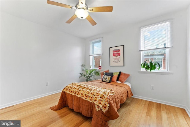 bedroom with ceiling fan, multiple windows, and hardwood / wood-style floors