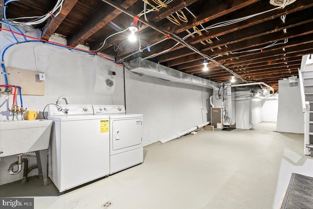 clothes washing area featuring heating unit, washer and clothes dryer, and sink