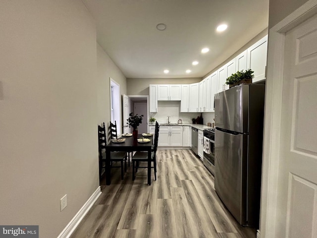 kitchen featuring stainless steel appliances, sink, white cabinets, and light hardwood / wood-style floors