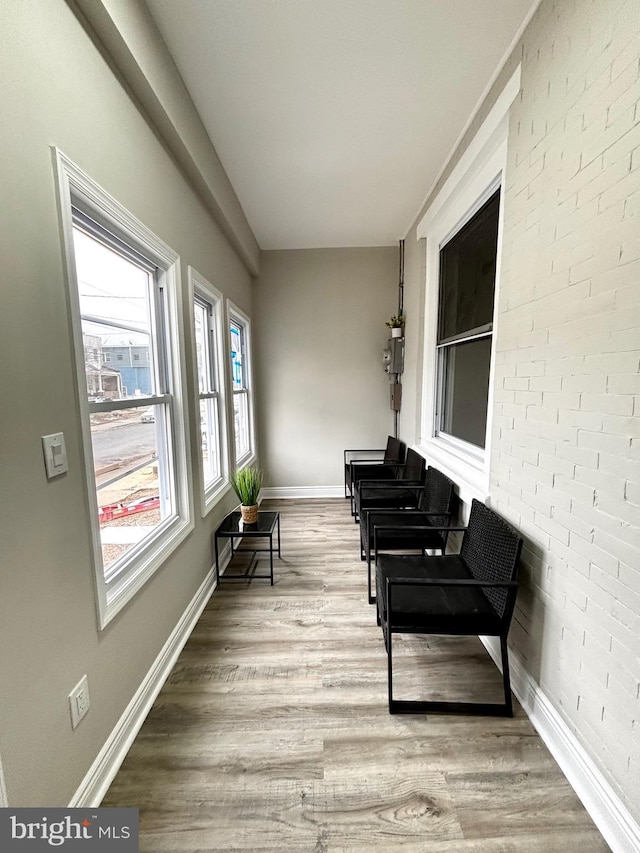 sitting room with brick wall and hardwood / wood-style floors