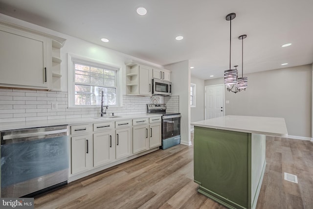 kitchen with white cabinetry, sink, stainless steel appliances, and a kitchen island