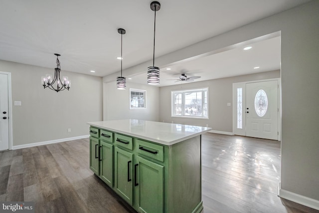 kitchen with pendant lighting, a center island, hardwood / wood-style flooring, green cabinetry, and ceiling fan with notable chandelier