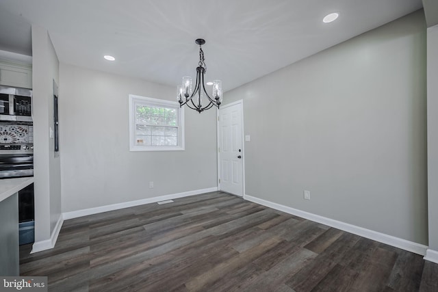 unfurnished dining area with dark wood-type flooring and an inviting chandelier