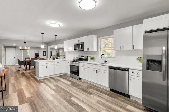 kitchen featuring decorative light fixtures, kitchen peninsula, decorative backsplash, white cabinetry, and stainless steel appliances