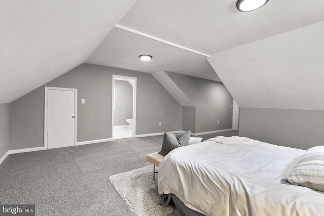 bedroom with ensuite bathroom, lofted ceiling, and carpet flooring