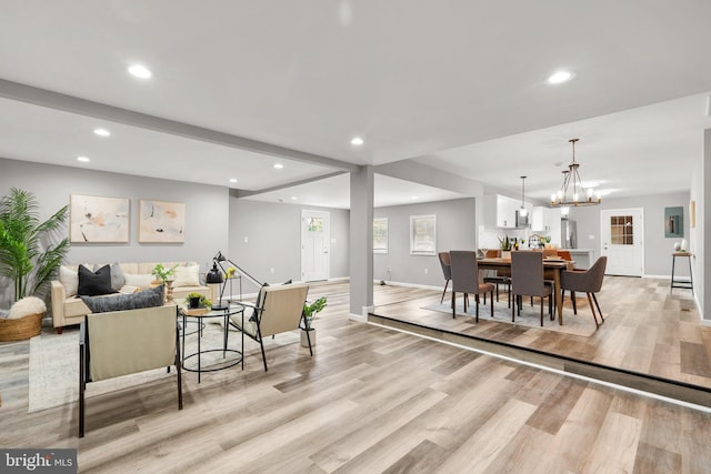 dining space with a notable chandelier, beamed ceiling, and light hardwood / wood-style flooring