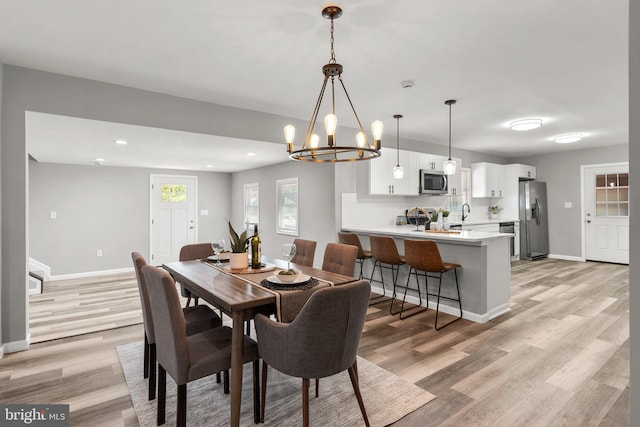 dining room with light hardwood / wood-style floors and an inviting chandelier