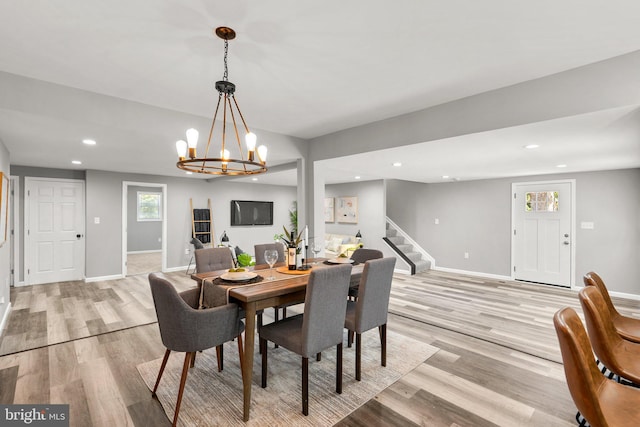 dining space featuring a healthy amount of sunlight, light wood-type flooring, and an inviting chandelier