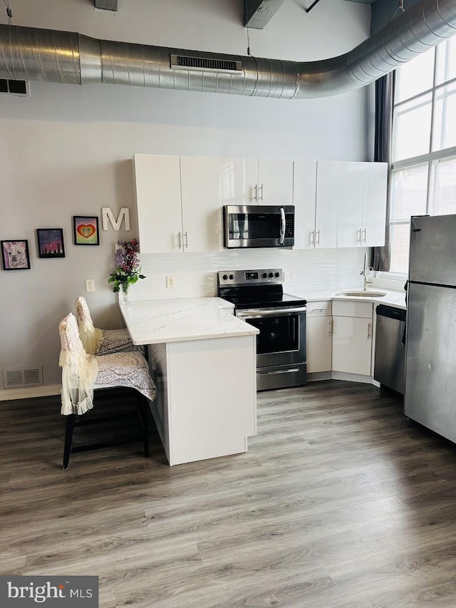 kitchen with light stone counters, sink, white cabinets, and stainless steel appliances