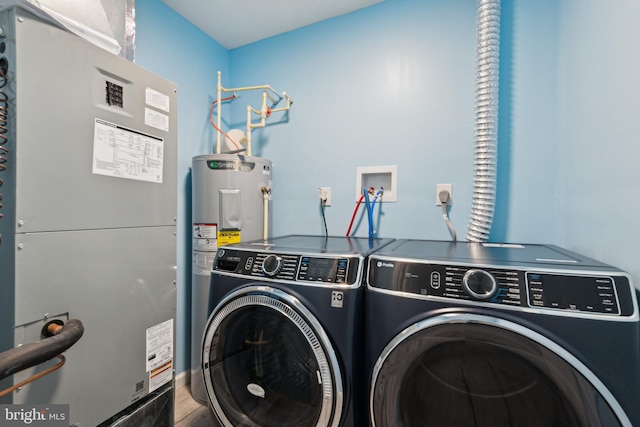 washroom featuring heating unit, water heater, and washing machine and clothes dryer