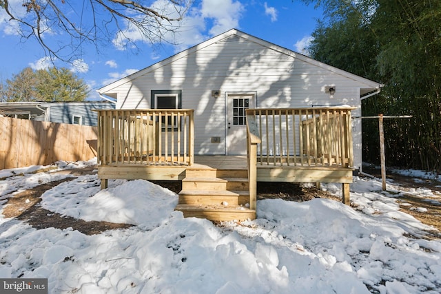 snow covered back of property with a deck