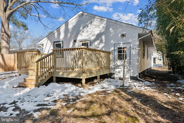 snow covered house with a wooden deck