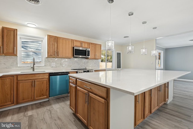 kitchen featuring a center island, decorative light fixtures, stainless steel appliances, sink, and light hardwood / wood-style flooring