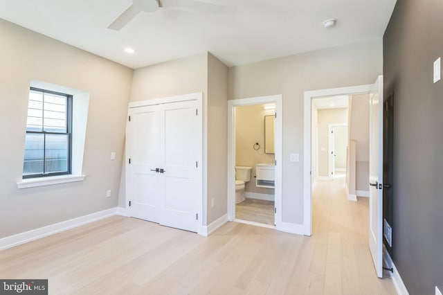 unfurnished bedroom featuring ceiling fan, connected bathroom, a closet, and light hardwood / wood-style flooring