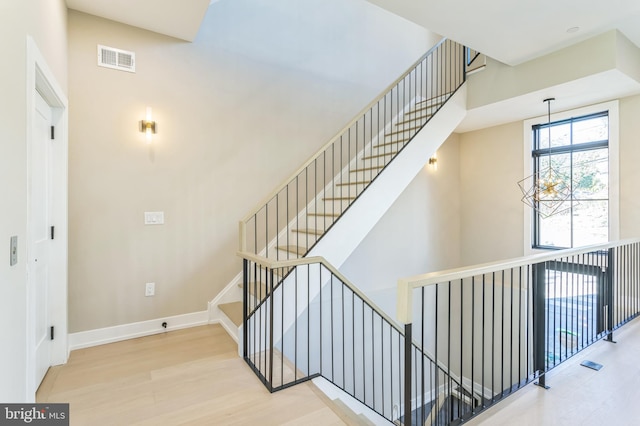 stairs with an inviting chandelier and hardwood / wood-style flooring